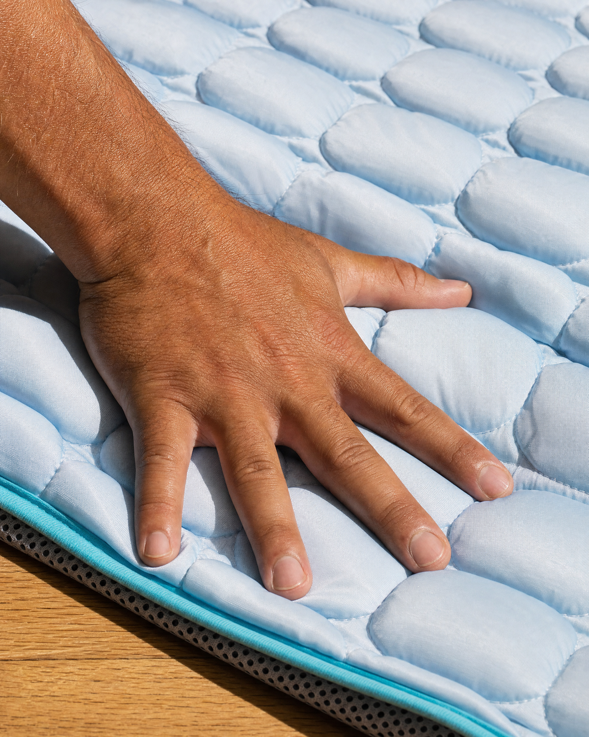 A hand pressing the quilted ice-silk surface of the PawFresco ChillMat