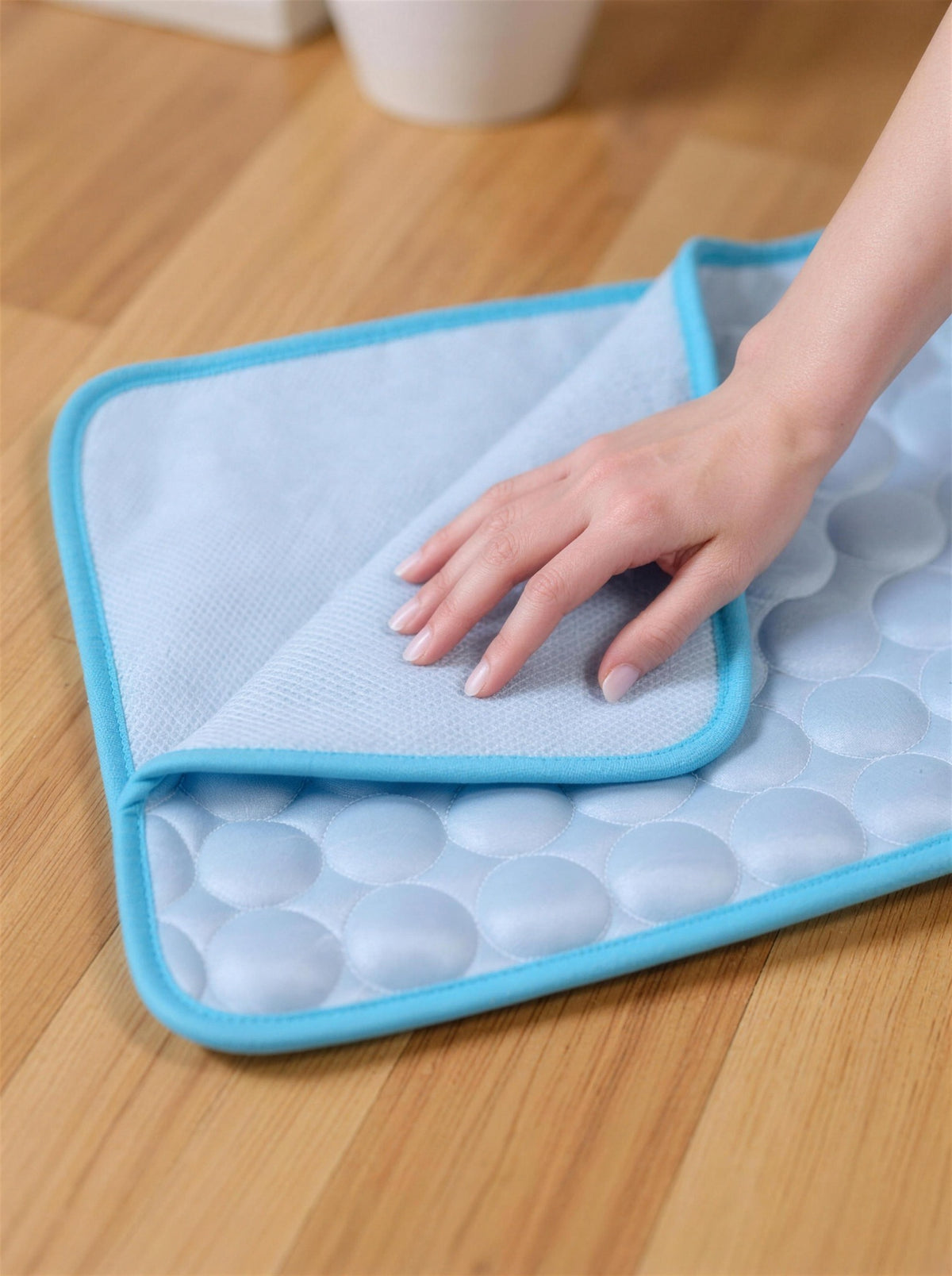 A hand pressing the quilted ChillMat surface — soft and cool to the touch